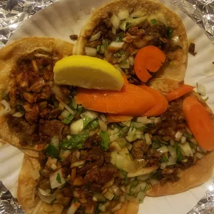 a plate of tacos with a slice of lemon