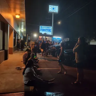 people sitting on the sidewalk at night