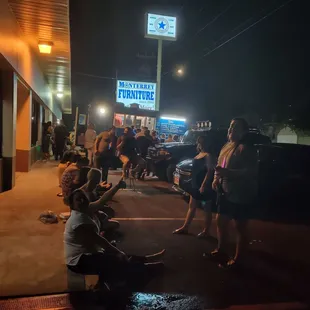 a group of people standing outside of a restaurant at night