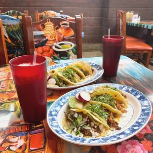 two plates of tacos and a drink