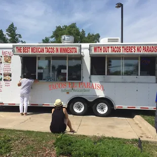 a hand holding a container of tacos