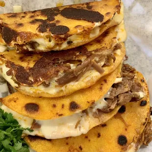 a stack of tacos with meat and cheese