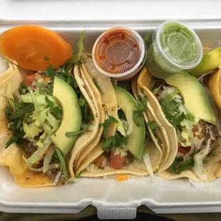 a variety of tacos in a styrofoam container