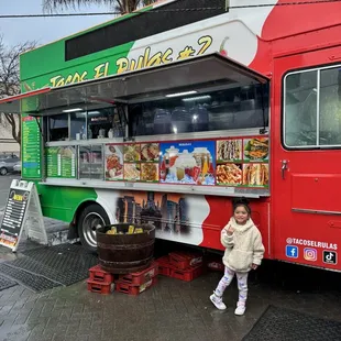 a little girl standing in front of a food truck