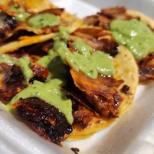 Pastor tacos covered in avo cilantro sauce