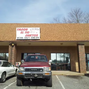 two cars parked in front of a tacos el tios restaurant