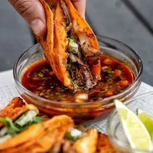 a person dipping a taco into a bowl