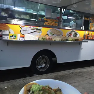 a person holding a plate of food in front of a food truck