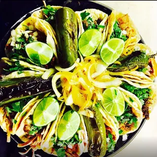 a plate of tacos with limes