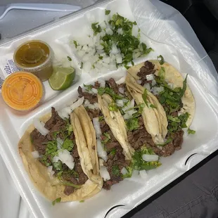 Order of tacos: Carne asada, salsa de chile de árbol (pink), salsa de chile jalapeño (green), onions, cilantro, limes