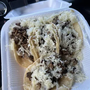 two tacoss in a styrofoam container