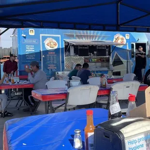 people sitting at tables under a blue tent