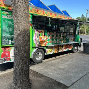 a food truck parked next to a tree