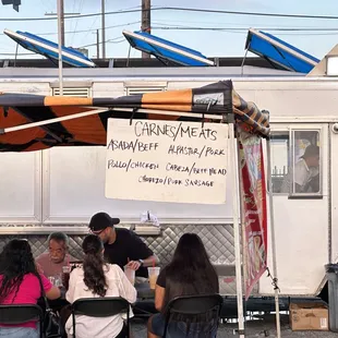 a group of people sitting around a food truck