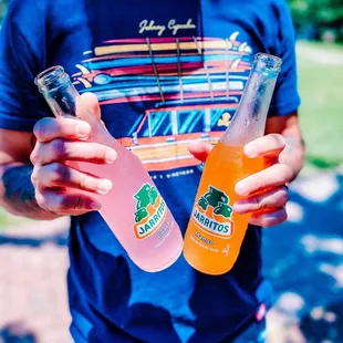 a man holding two drinks