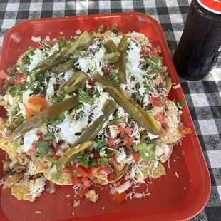 Nachos de pollo con tomate cebolla cilantro  frijol queso salsa verde crema y chile jalapeño algo bien