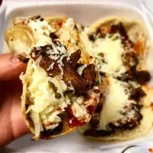 a hand holding a taco in a styrofoam container