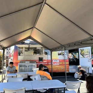 people sitting at tables under a tent
