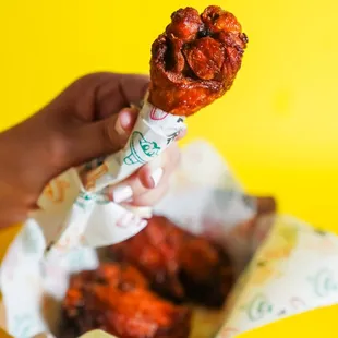 a hand holding a chicken wing
