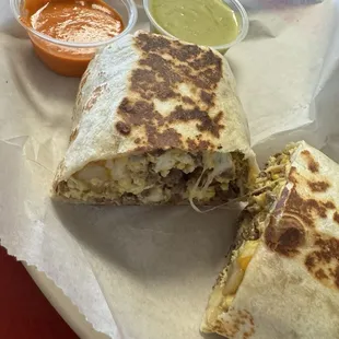 Steak breakfast burrito paired with green avocado salsa and orange habanero salsa