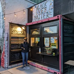 two people standing outside of a restaurant