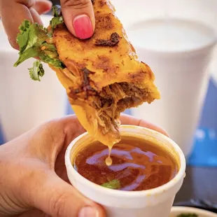 a hand dipping a piece of quesadilla
