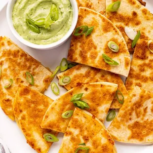 a plate of quesadillas with a bowl of guacamole