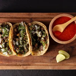 three tacos on a cutting board with salsa