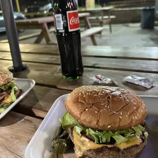 a burger and a coke on a picnic table