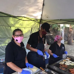 a group of people preparing food under a tent