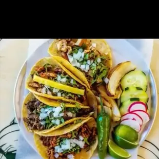 a plate of tacos with pickles and cucumbers
