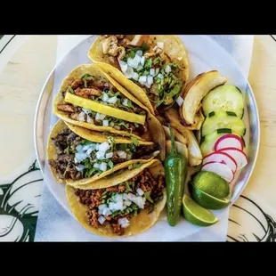 a plate of tacos with pickles and cucumbers