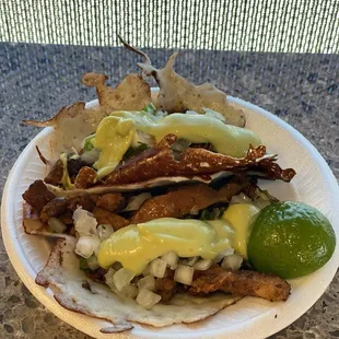 Two keto tacos with the standard toppings that are included for free  and a side of lime.