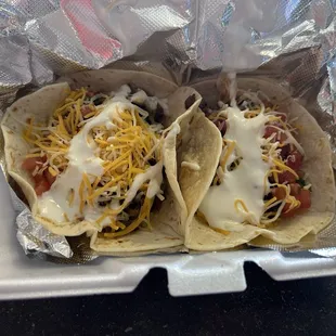 Two tacos, one is ground beef and the other is steak both have cheese, pico, and sour cream!