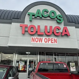 a red truck parked in front of a tacoss toluca store