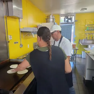 two people preparing food in a kitchen