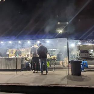 a man standing in front of a food stand