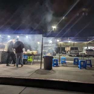 a group of people standing outside a taco stand