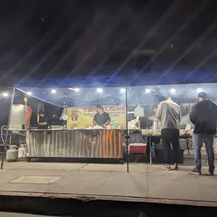 a group of people standing in front of a taco stand