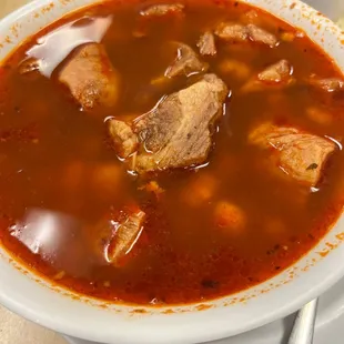 a bowl of soup with meat and tortillas