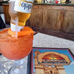 a bottle of beer being poured into a margarita