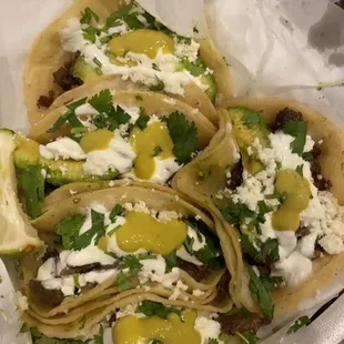 Beef fajita tacos with cilantro, sour cream, queso fresco, and salsa verde.