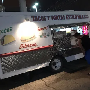 a woman standing in front of a taco truck