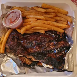 ribs and french fries in a styrofoam container