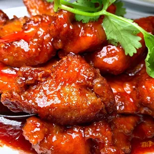 a plate of chicken wings with sauce and garnish