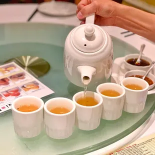 a person pouring tea into cups