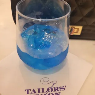 a glass of blue liquid on a napkin