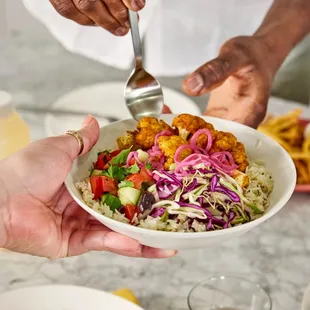 two hands holding a plate of food