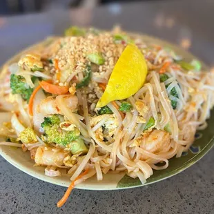 a plate of noodles with shrimp and broccoli