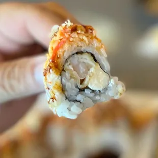 a hand holding a piece of sushi